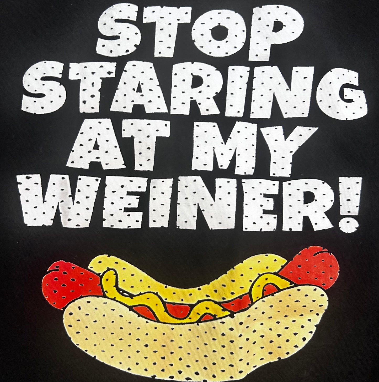 Black t-shirt with a hot dog graphic and text 'STOP STARING AT MY WEINER!' on a black background