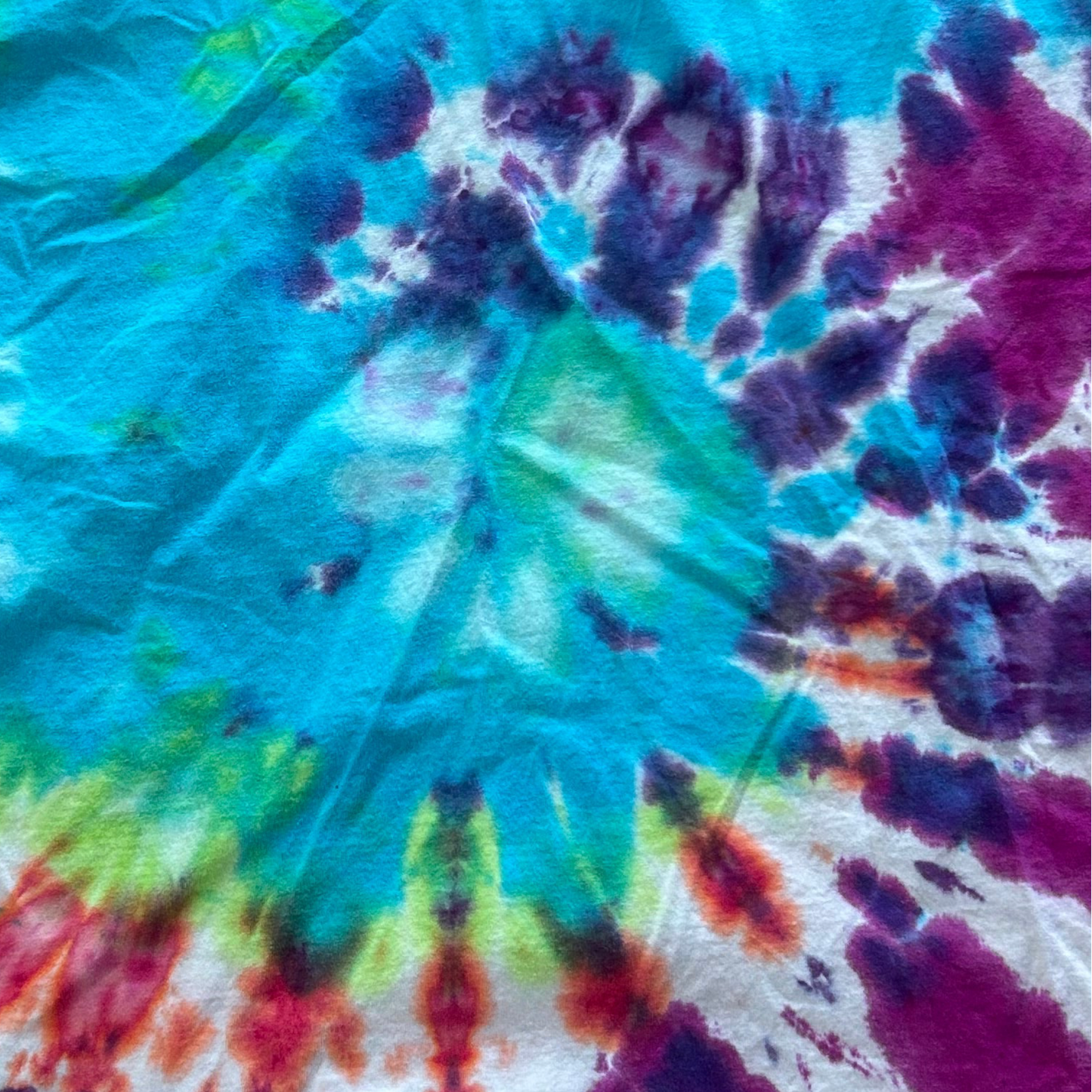 Close-up of a tie-dye tee shirt with vibrant colors including blue, green, red, and purple.