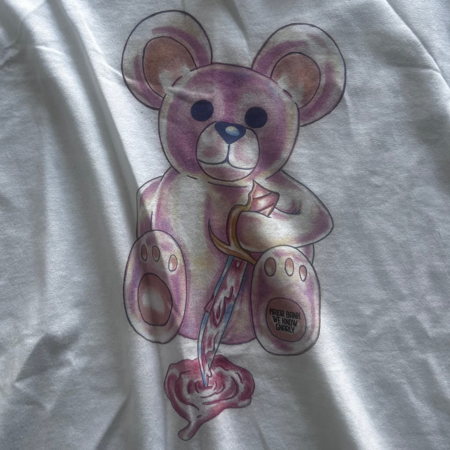 White t-shirt with a crazy pink teddy bear design on a plain background